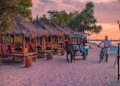 Seorang wisatawan menikmati matahari tenggelam di Pantai Pink, Lombok, Nusa Tenggara Barat. Foto: Wirestock/Getty Images